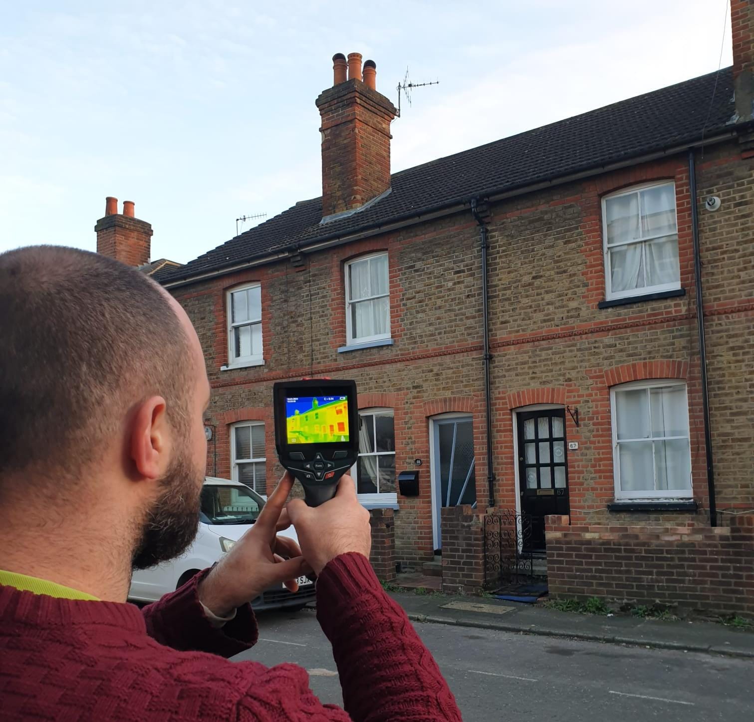 Energy Champion Sam using a thermal imaging camera outside a house.