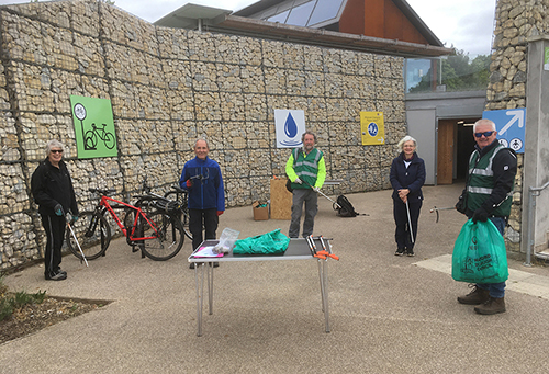 Older volunteers litter picking with large bag of rubbish