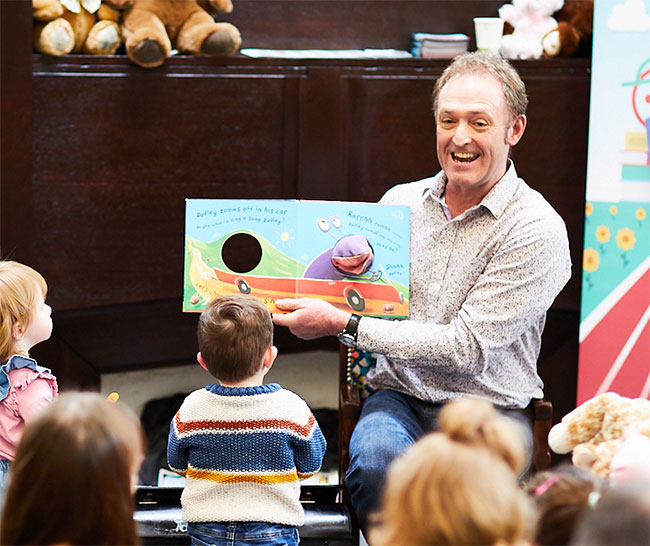 A man telling a story to a group of young children