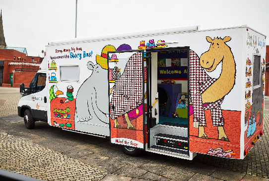 A large van (story bus) with various children's story characters covering the outside