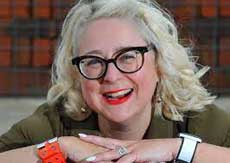 Smiling lady with long blond hair wearing black framed glasses