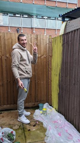 Alek painting a fence at his homeless shelter
