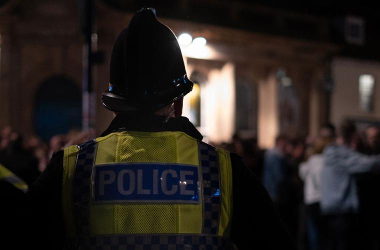 Back of a policeman facing a crowd at night 941 x 641px