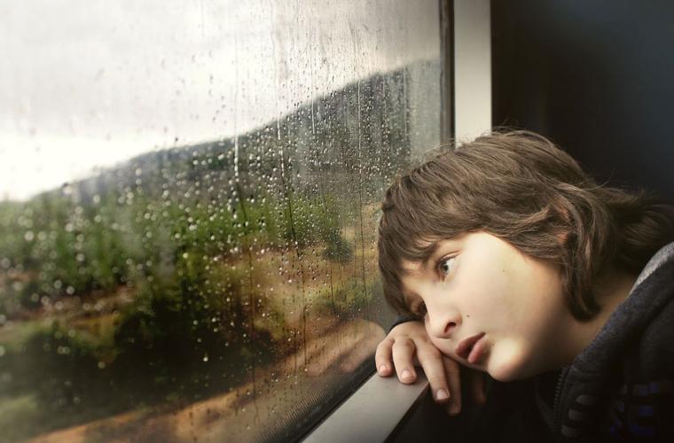 Boy looking out a rainy window