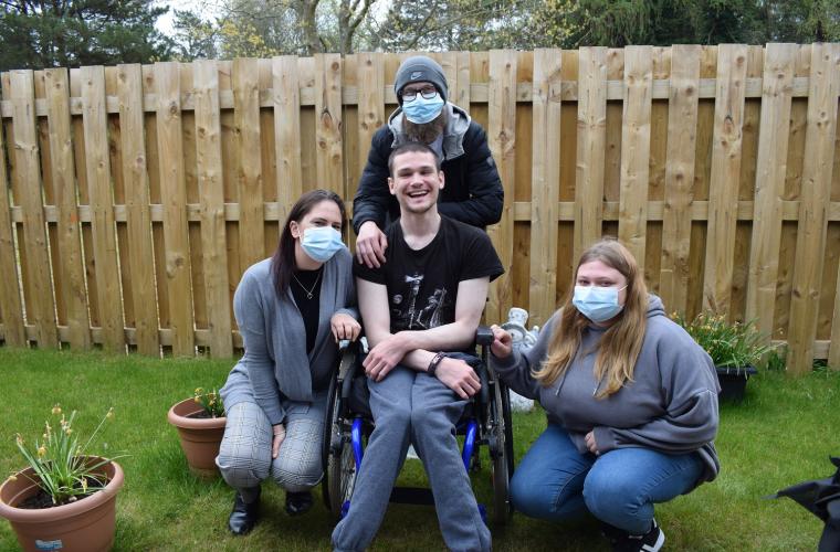 Person who has been helped by OPE housing smiling sitting with his carers