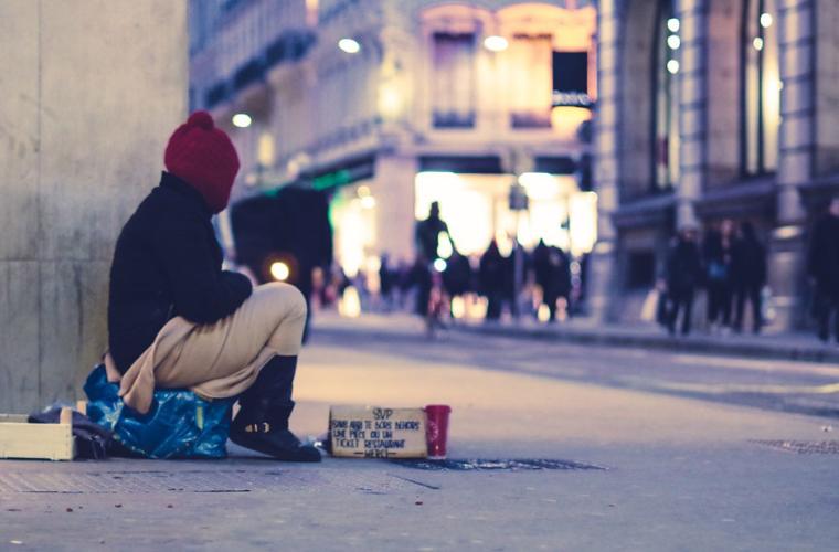 Homeless man sitting on the box on the street 