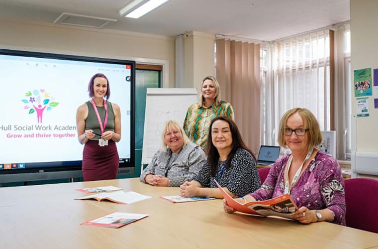 A group of women working on the Hull project. They are in a meeting room with a projector.