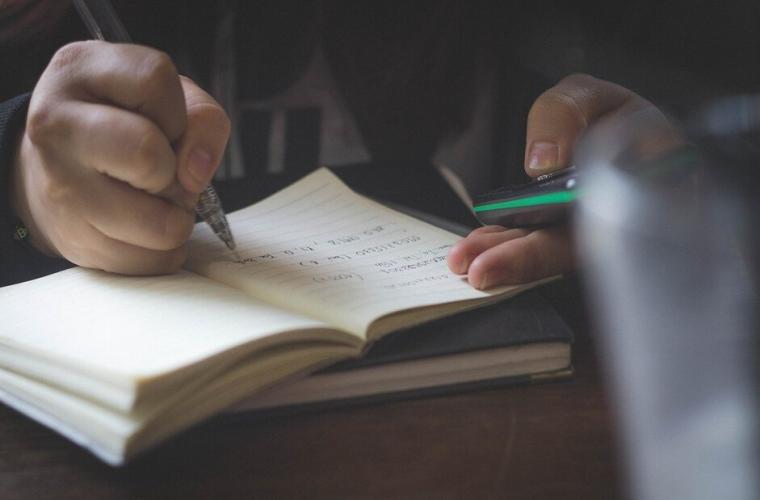 Picture of someone writing in a notebook and reading