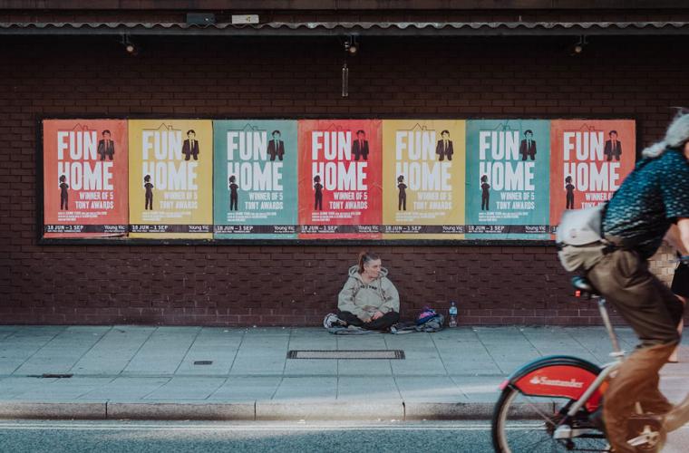 Man riding a bike passing by a homeless woman