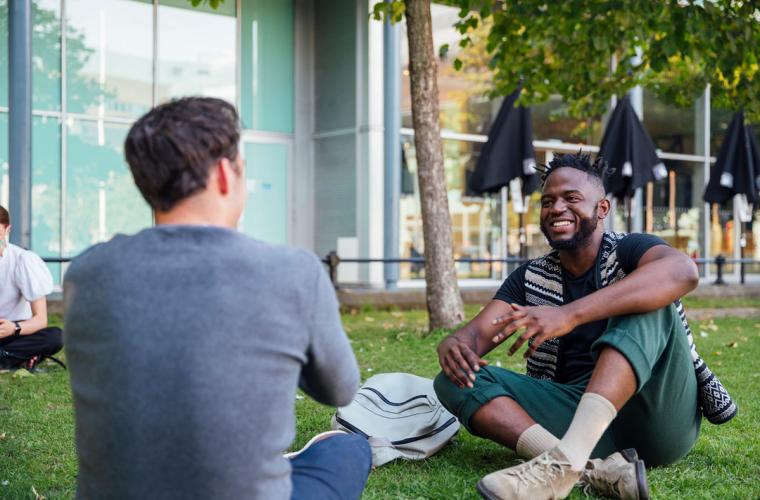 Two men sitting on grass laughing