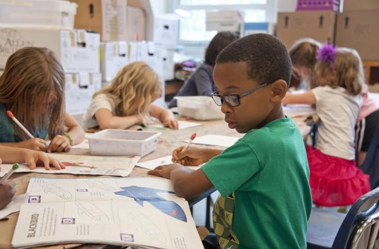 Young children sharing a large desk and school working 