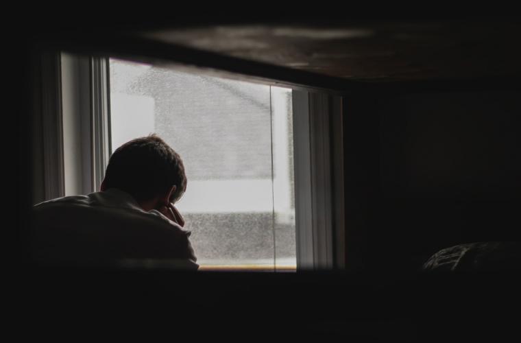 Person in a darkened room looking outside a window 1400 x 900