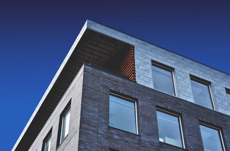 A high rise grey building against a blue sky