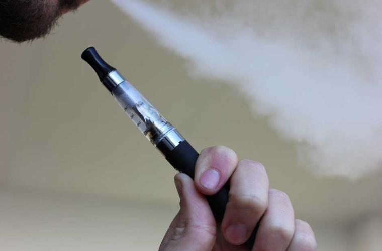 Part of a man's face while he smokes an e-cigarette