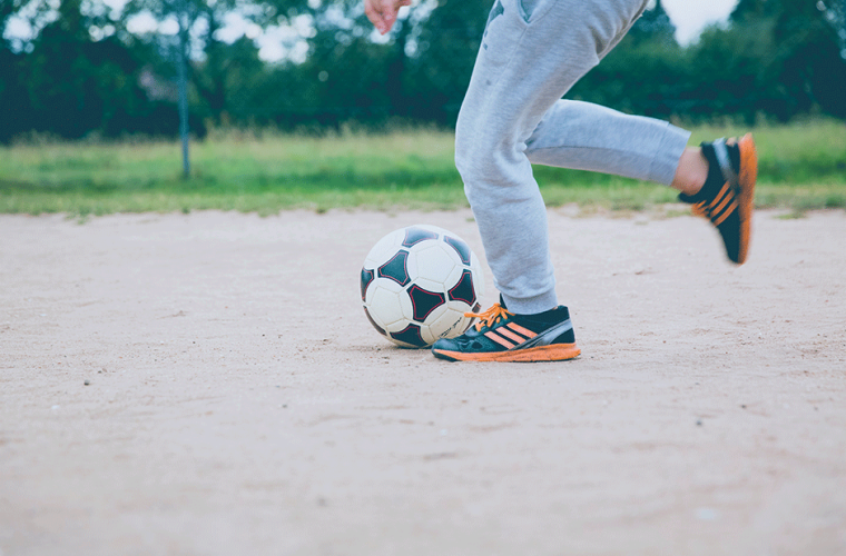 legs running behind a ball in a field 