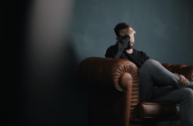 Man sat down in a darkened room looking distressed