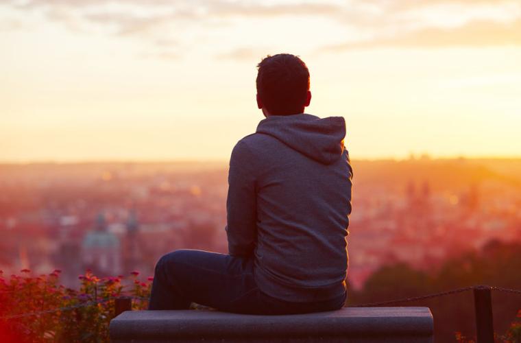 photo of young man looking at the city below