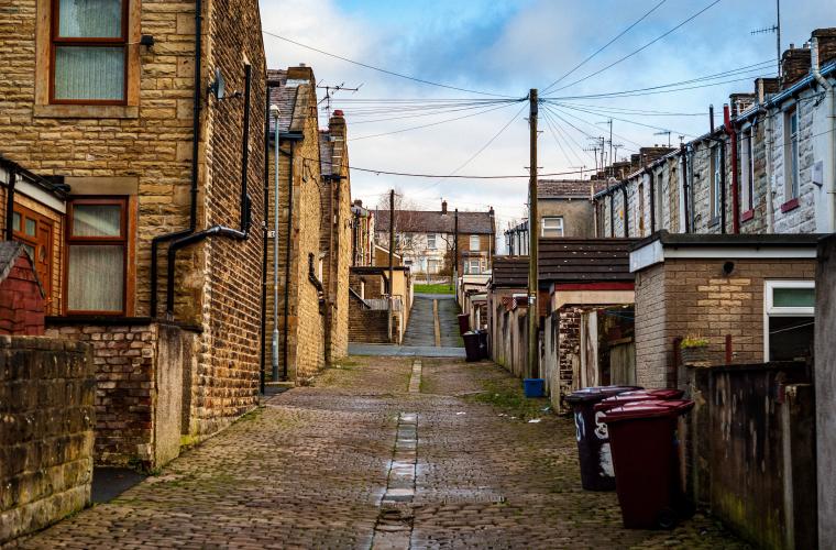 Empty street with houses either side, blue sky with some clouds.
