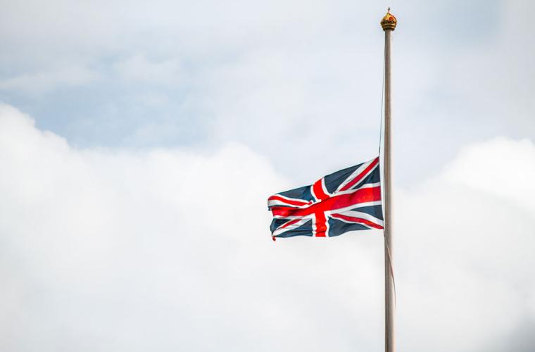 A union jack flag flown at half mast against an overcast sky