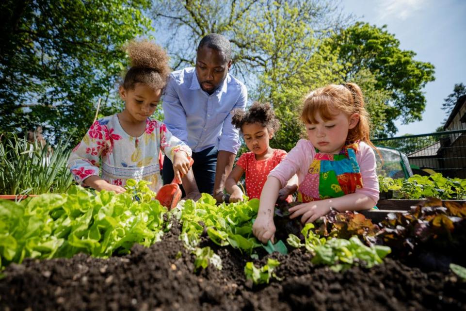 Adult with three children in community garden 