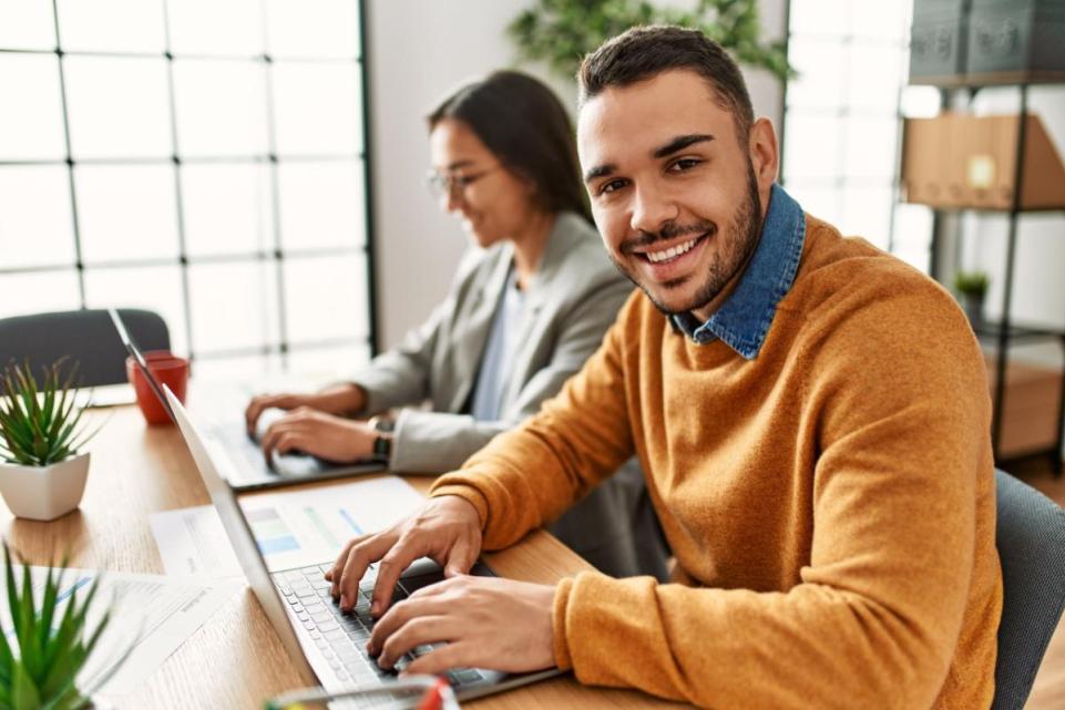 Man smiling while typing on a computer