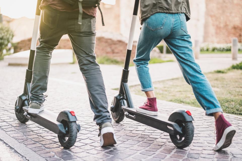 Two people riding electric scooters
