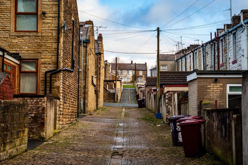Empty street with houses either side, blue sky with some clouds.